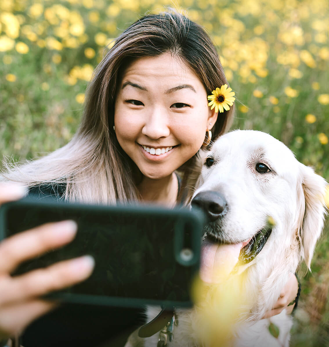 woman taking a photo with a golden retriever outdoors