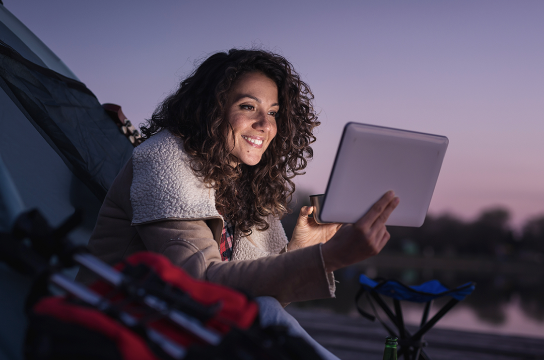 A woman using a laptop beside her car on a getaway