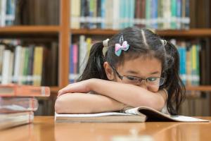 Young girl wears reading glasses to correct blurred vision from myopia