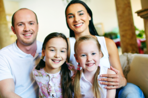 Family of four sits together on a couch