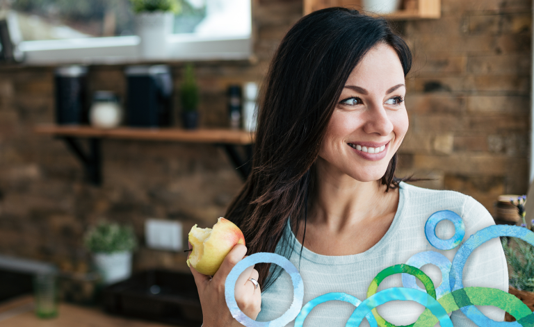 woman smiling and holding an apple in a kitchen