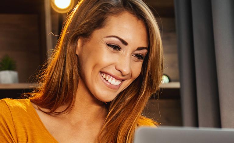 woman smiling and using a laptop