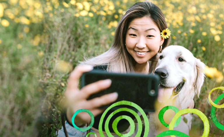 woman taking a photo with a golden retriever outdoors
